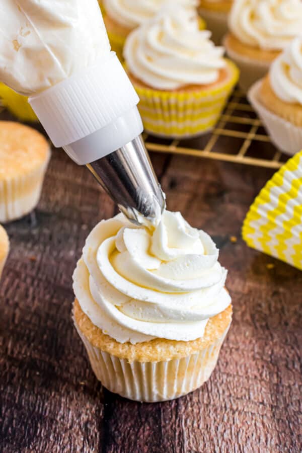 Lemon frosting being piped onto a lemon cupcake.