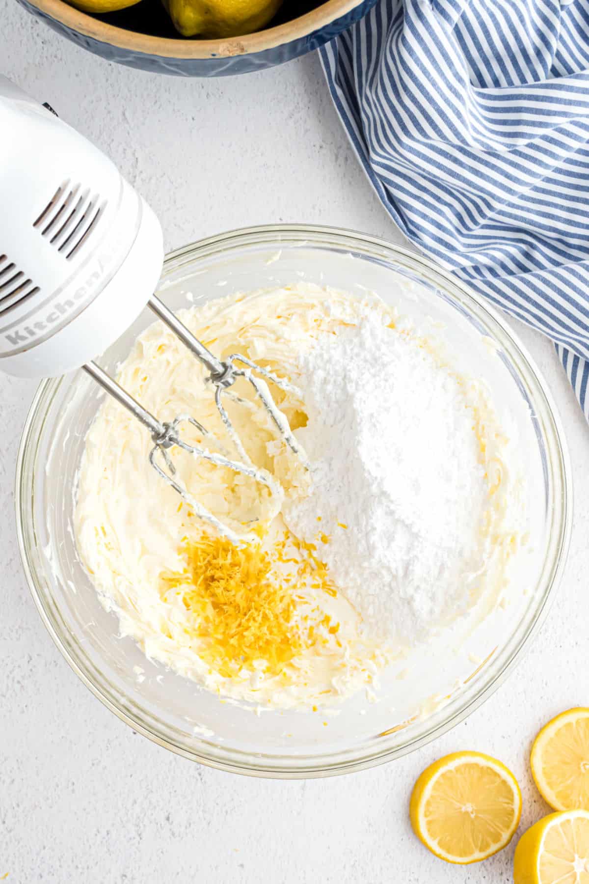 Lemon frosting ingredients in a bowl with a hand mixer.