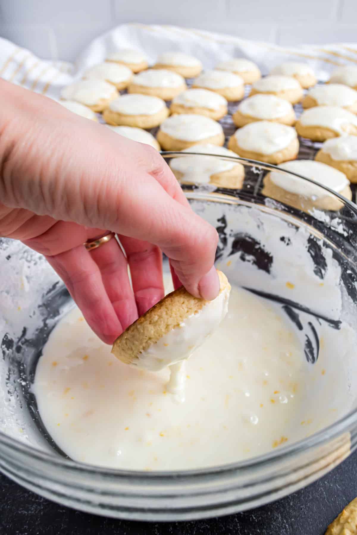 Cookie being dipped in bowl of lemon icing.