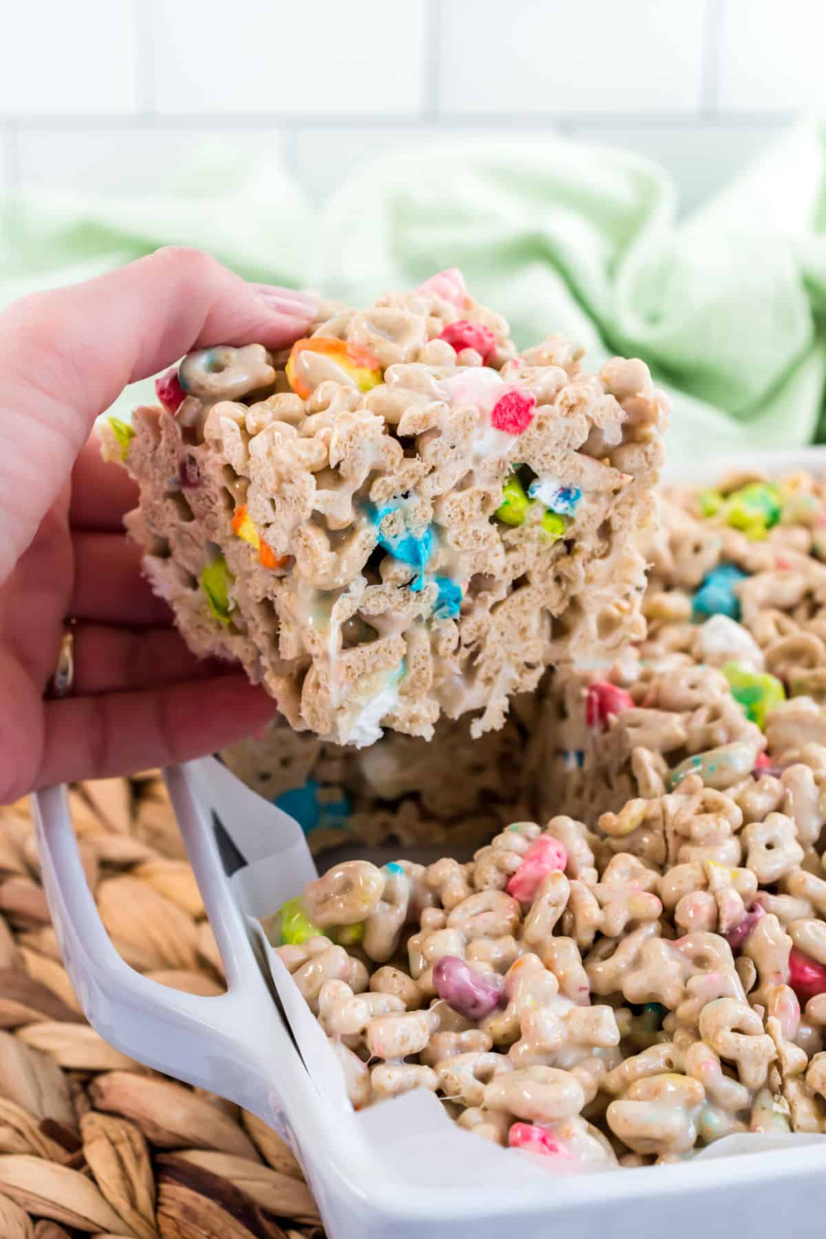 Lucky charms treat bar being pulled out of the square baking dish.