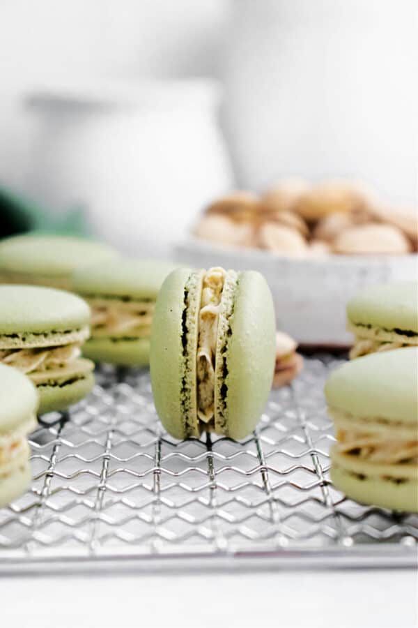 Pistachio macarons on a wire cooling rack.