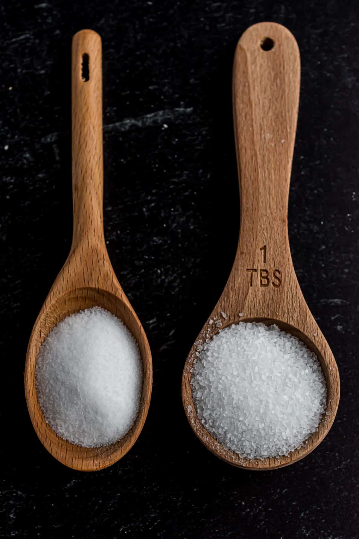 Two wooden spoons showing the difference between table salt and kosher salt.