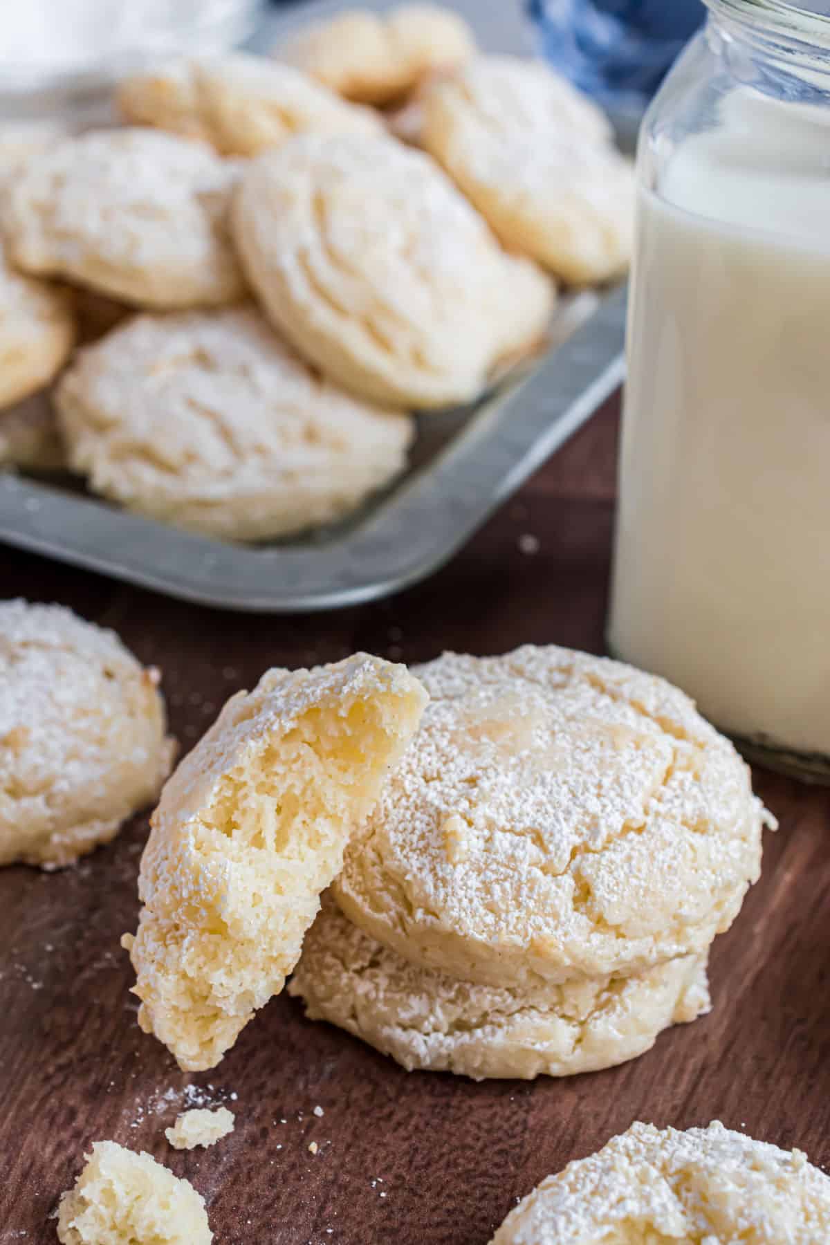 Cheesecake cookies stacked on table, one broken open.