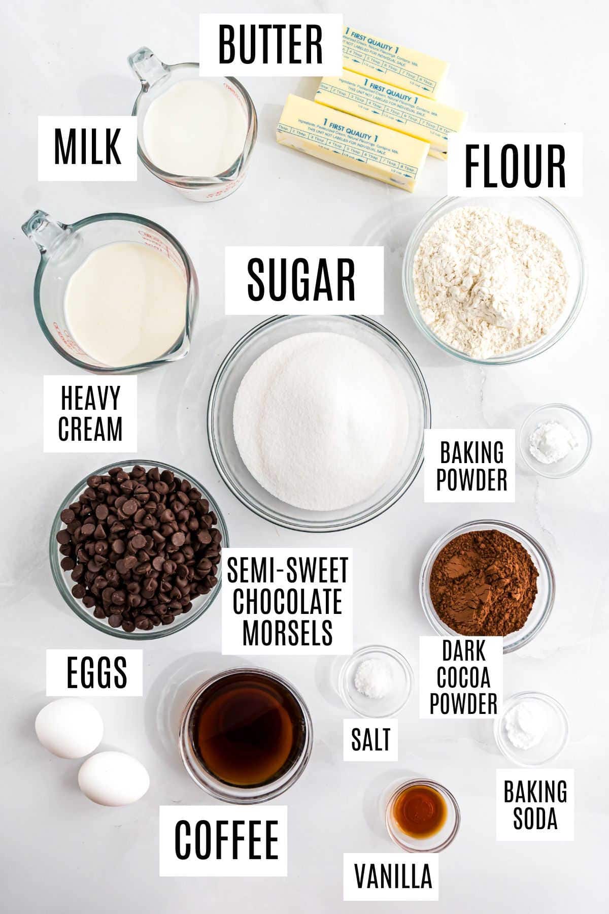 Top down view of labeled baking ingredients—flour, sugar, butter, eggs, chocolate, cream, cocoa, and more—perfect for making classic treats like ding dong cake.