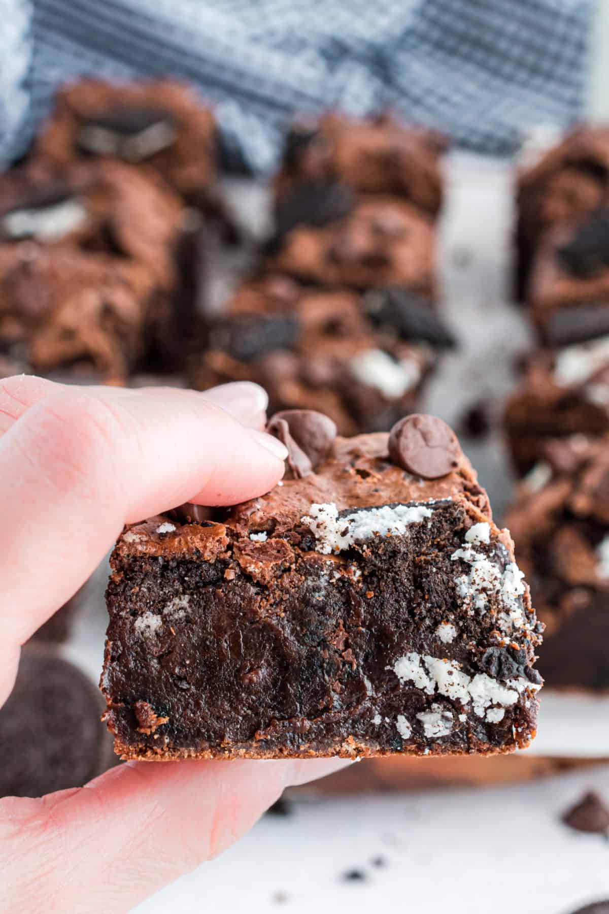 Hand holding a thick and fudgy Oreo brownie.