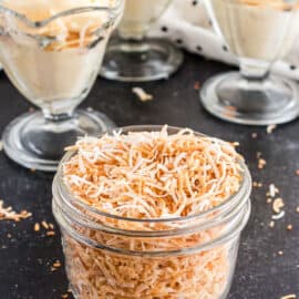 Toasted coconut in a small jar with ice cream in background.