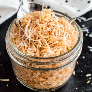 Toasted coconut in a small glass mason jar.