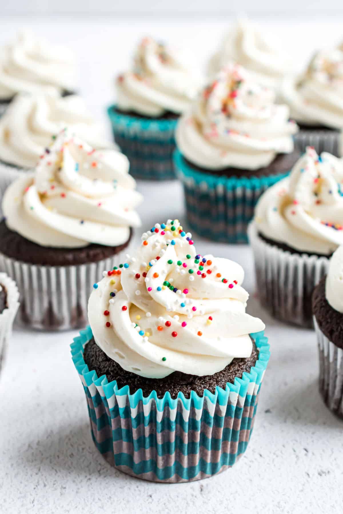 Vanilla buttercream frosting piped onto chocolate cupcakes with sprinkles.