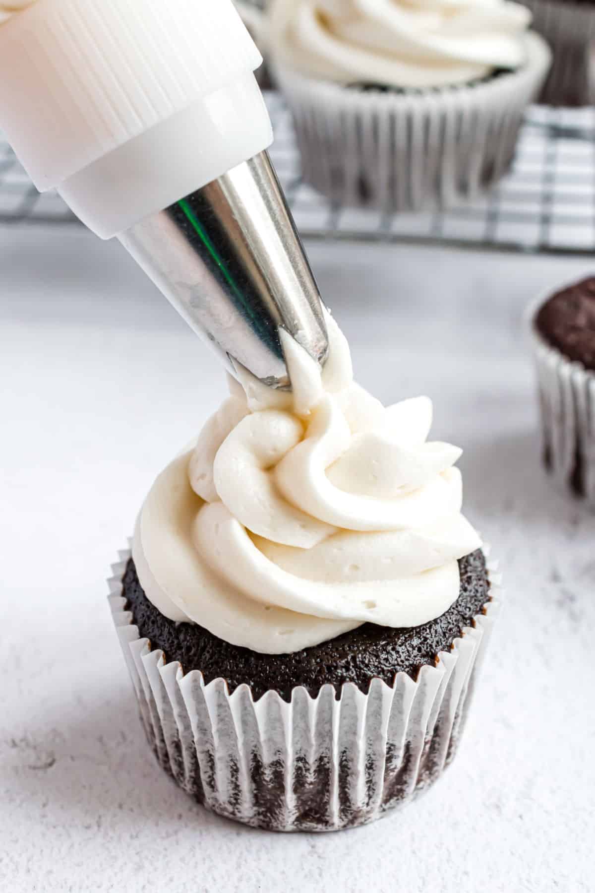 Vanilla frosting piped onto chocolate cupcakes.
