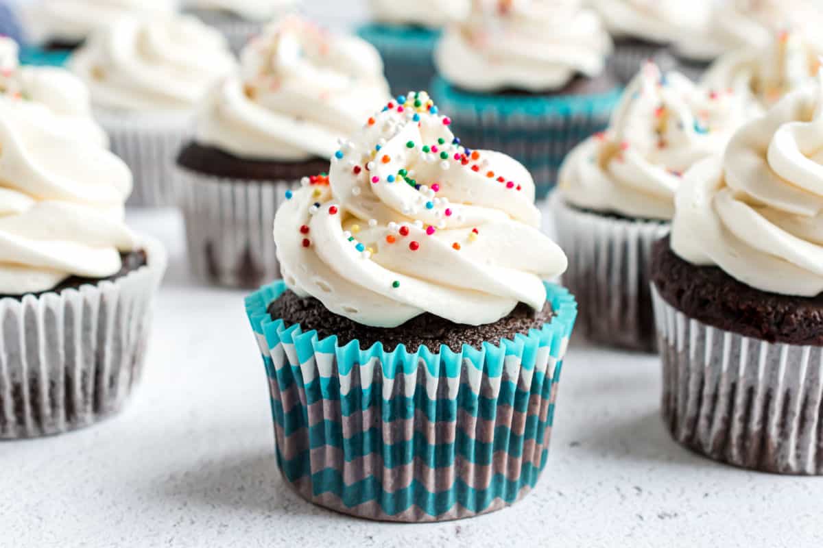 Vanilla frosting on chocolate cupcakes with colorful non pariels.