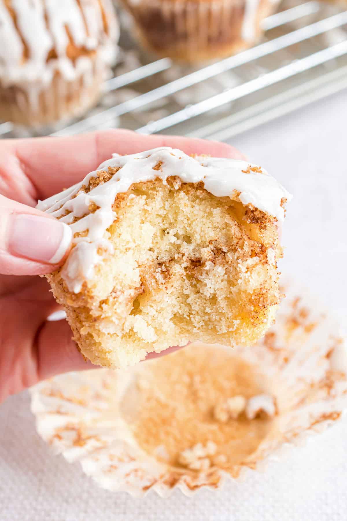 Apple muffins with a ribbon of cinnamon and vanilla icing and a bite taken.