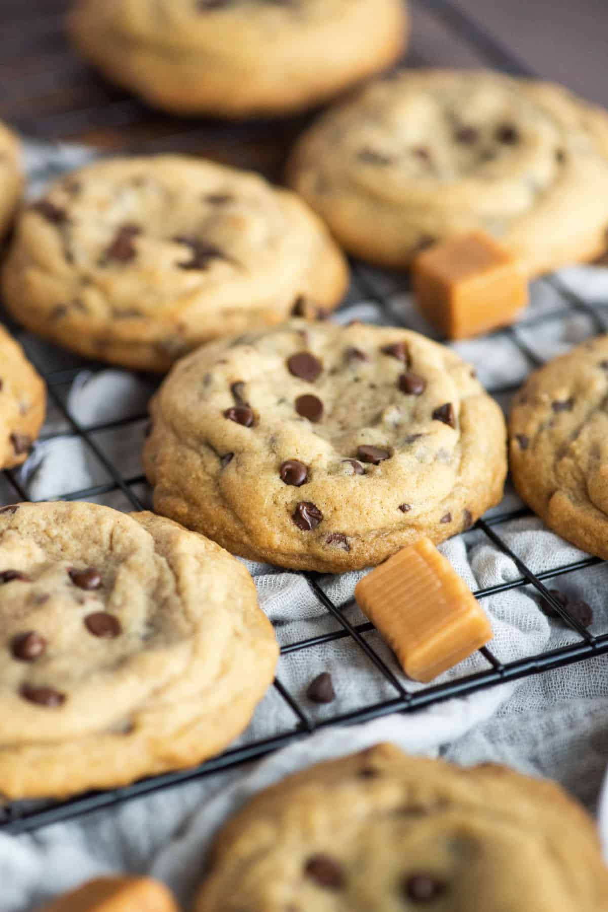 Chocolate chip cookies with caramels on a black wire cooling rack.