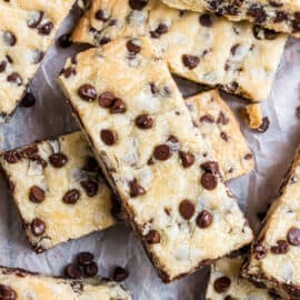 Chocolate chip shortbread bars stacked on parchment paper.