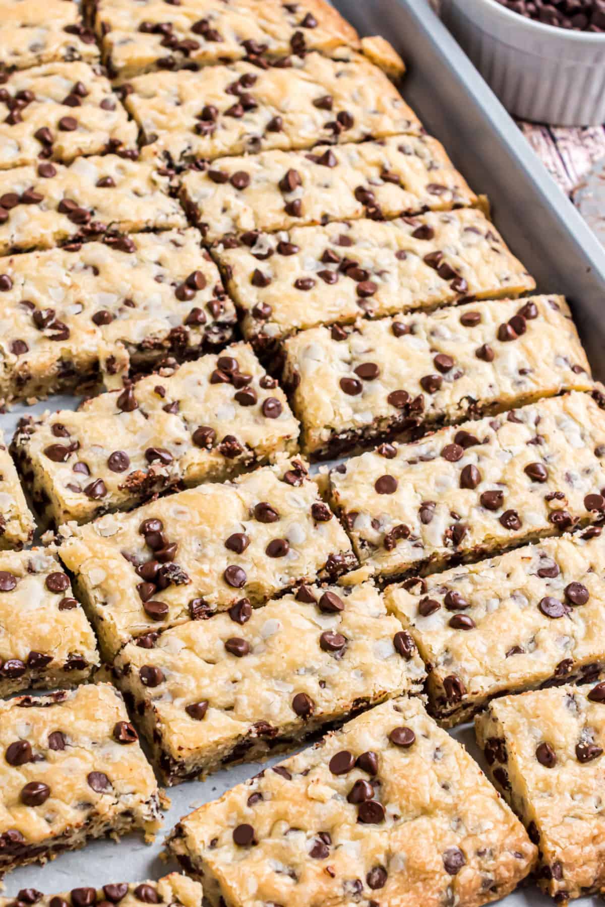 Rectangle shortbread cookies with chocolate chips on a baking sheet.