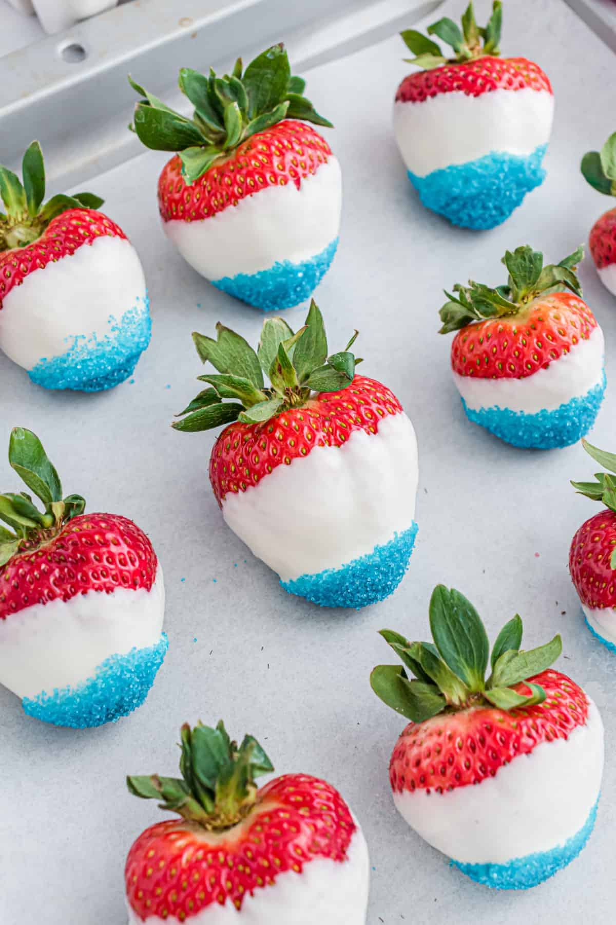 Red white and blue covered strawberries on parchment paper.