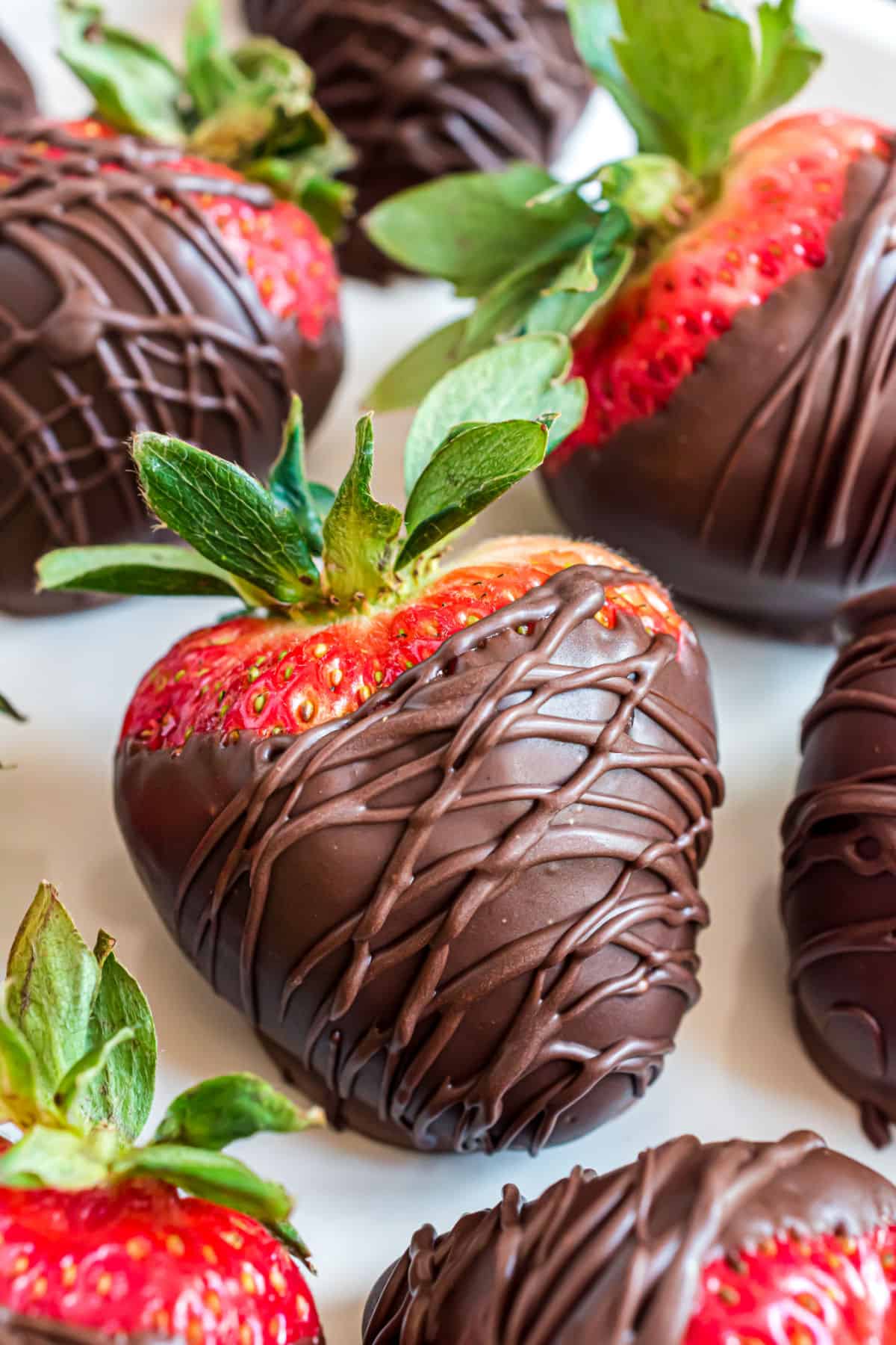 Chocolate covered strawberries on a piece of parchment paper.