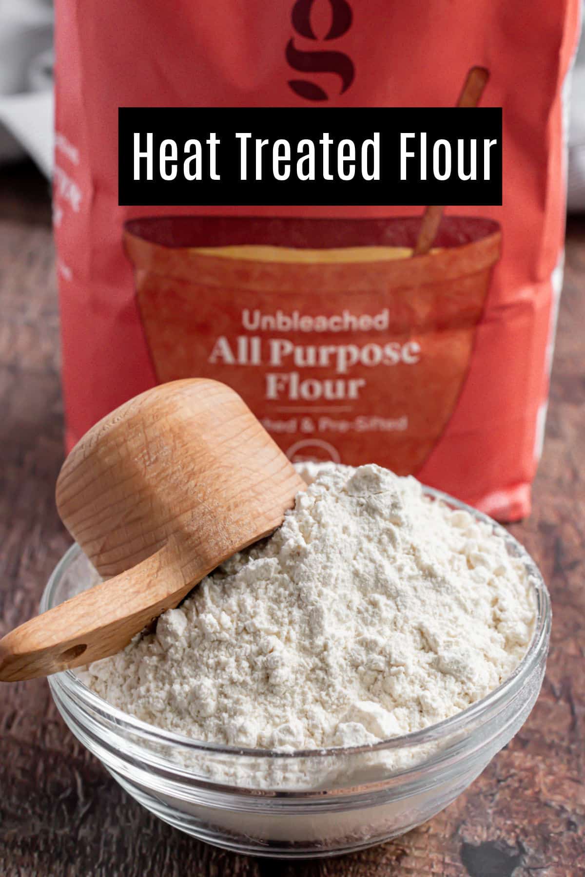 Glass bowl with flour and red bag of flour in background.