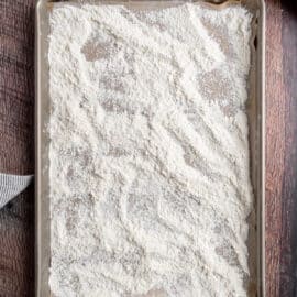 Metal cookie sheet covered with flour to bake.