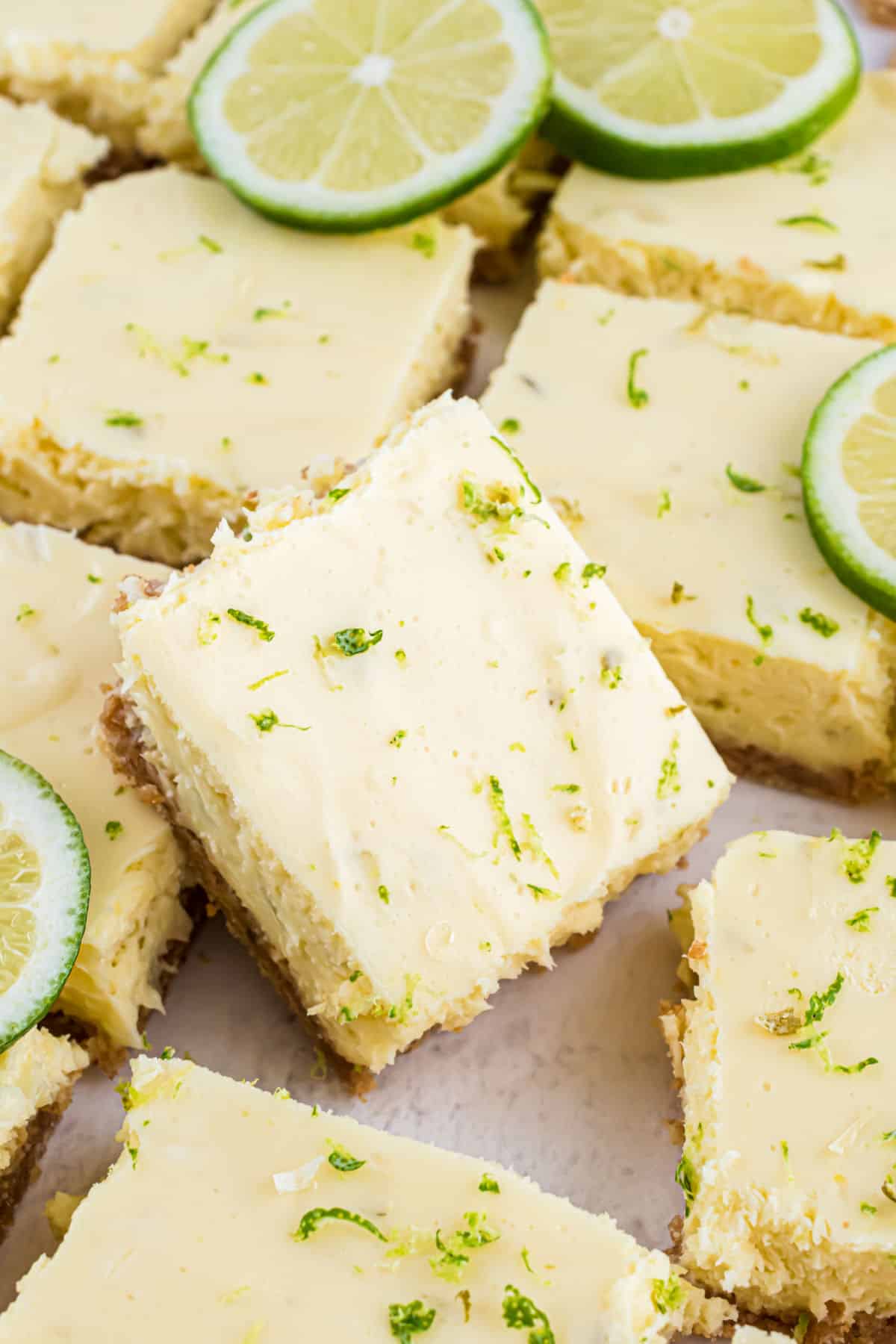 Key lime pie bars cut into squares on parchment paper.