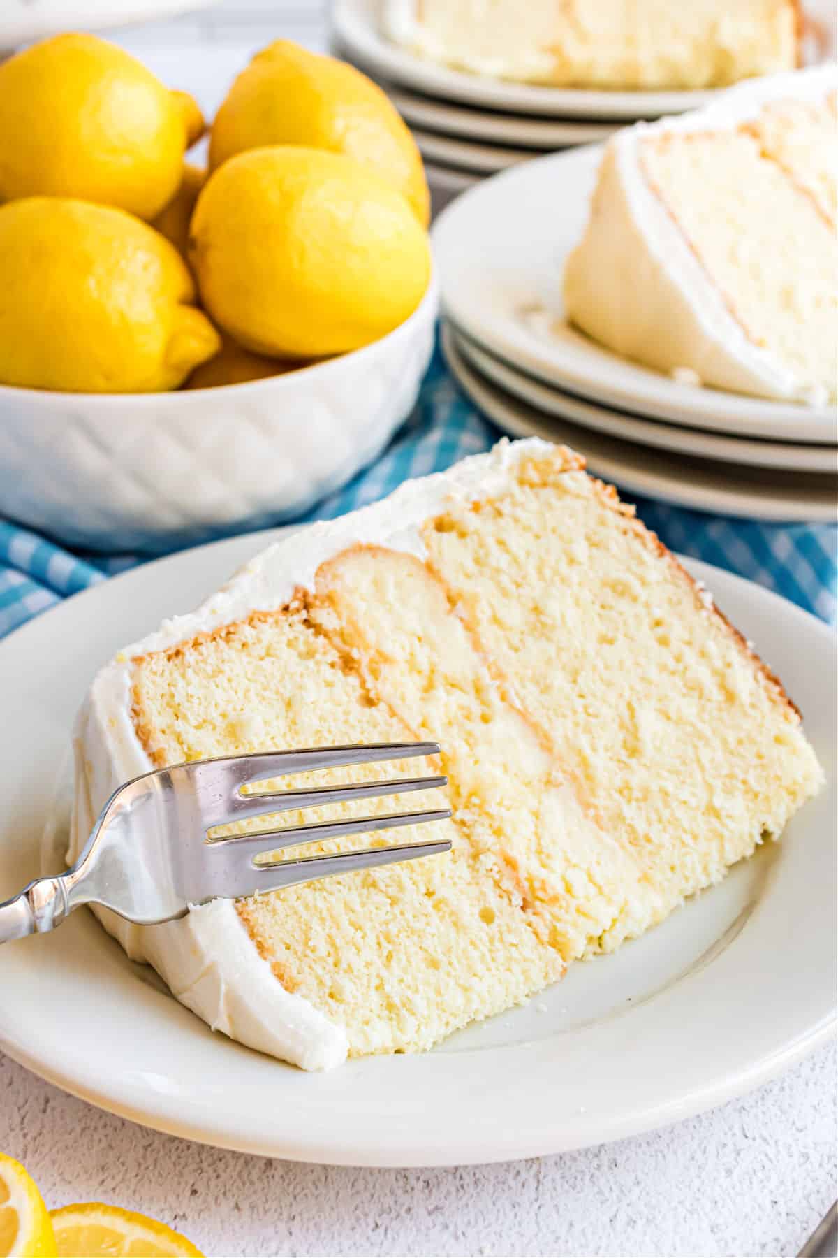 Slice of lemon cheesecake cake on a white plate with a fork.