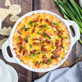 Loaded potato chip dip in a baking dish and topped with bacon.