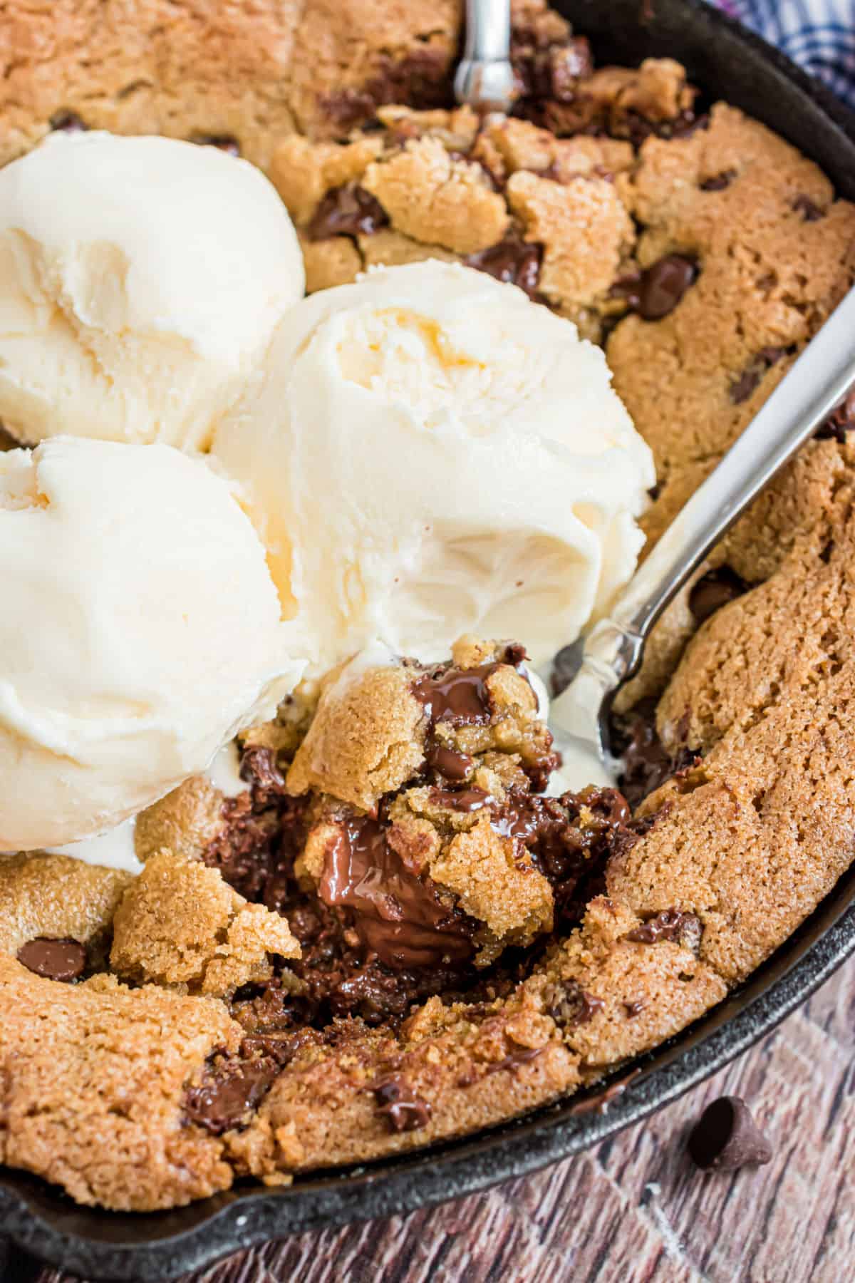 Gooey skillet cookie with spoons and ice cream.