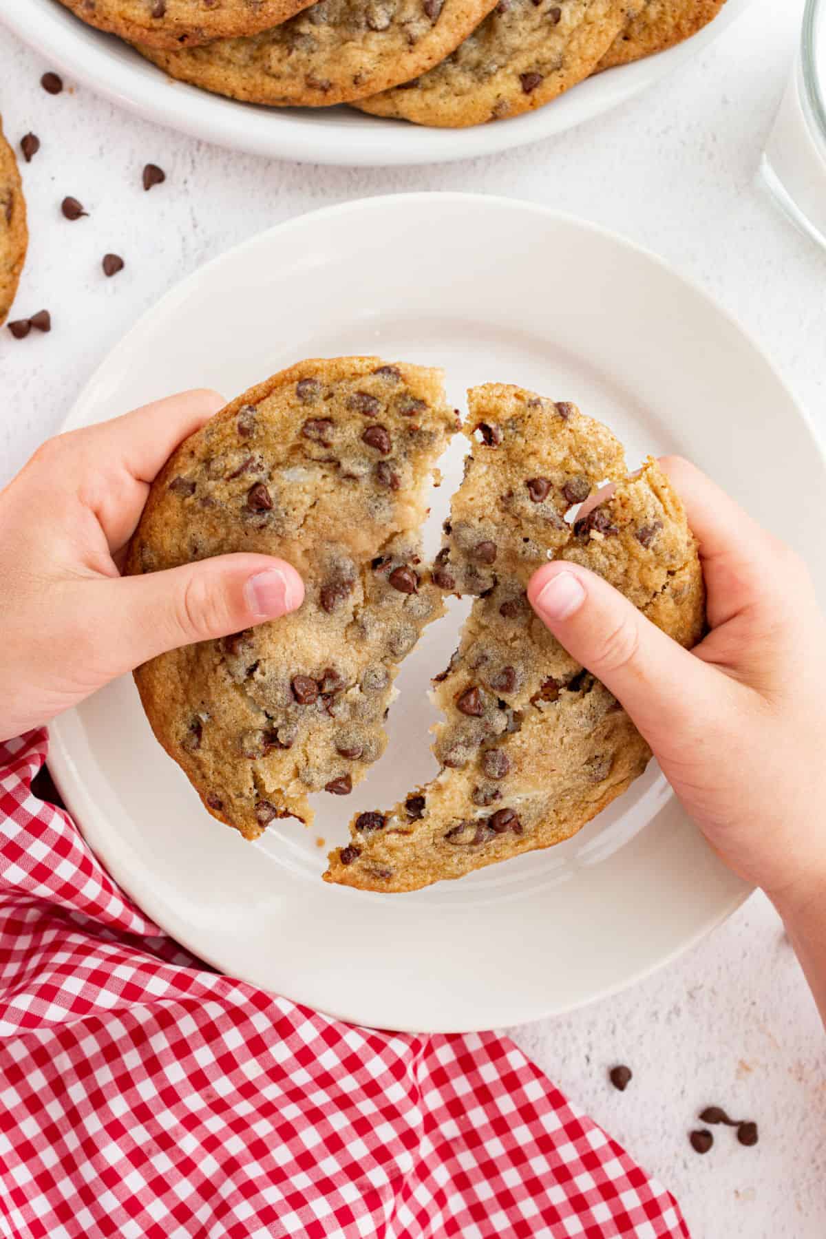 Chocolate chip cookie with cheesecake filling being broken in half.