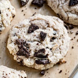 Oreo cheesecake cookie on parchment paper, topped with extra crushed oreos.