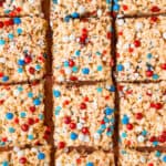 Rice krispy treats cut into squares and decored with red white and blue sprinkles.