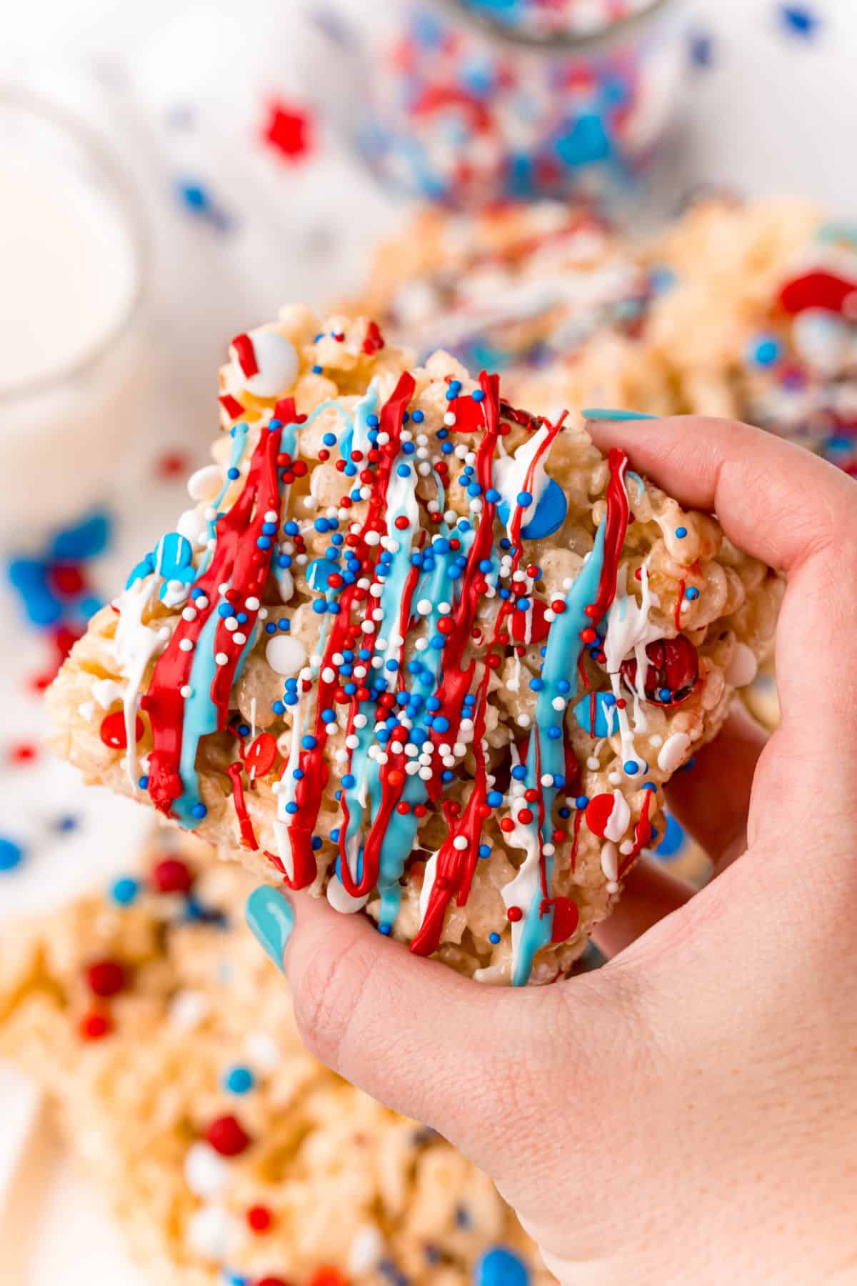 Red white and blue sprinkled rice crispy treat being held up close.