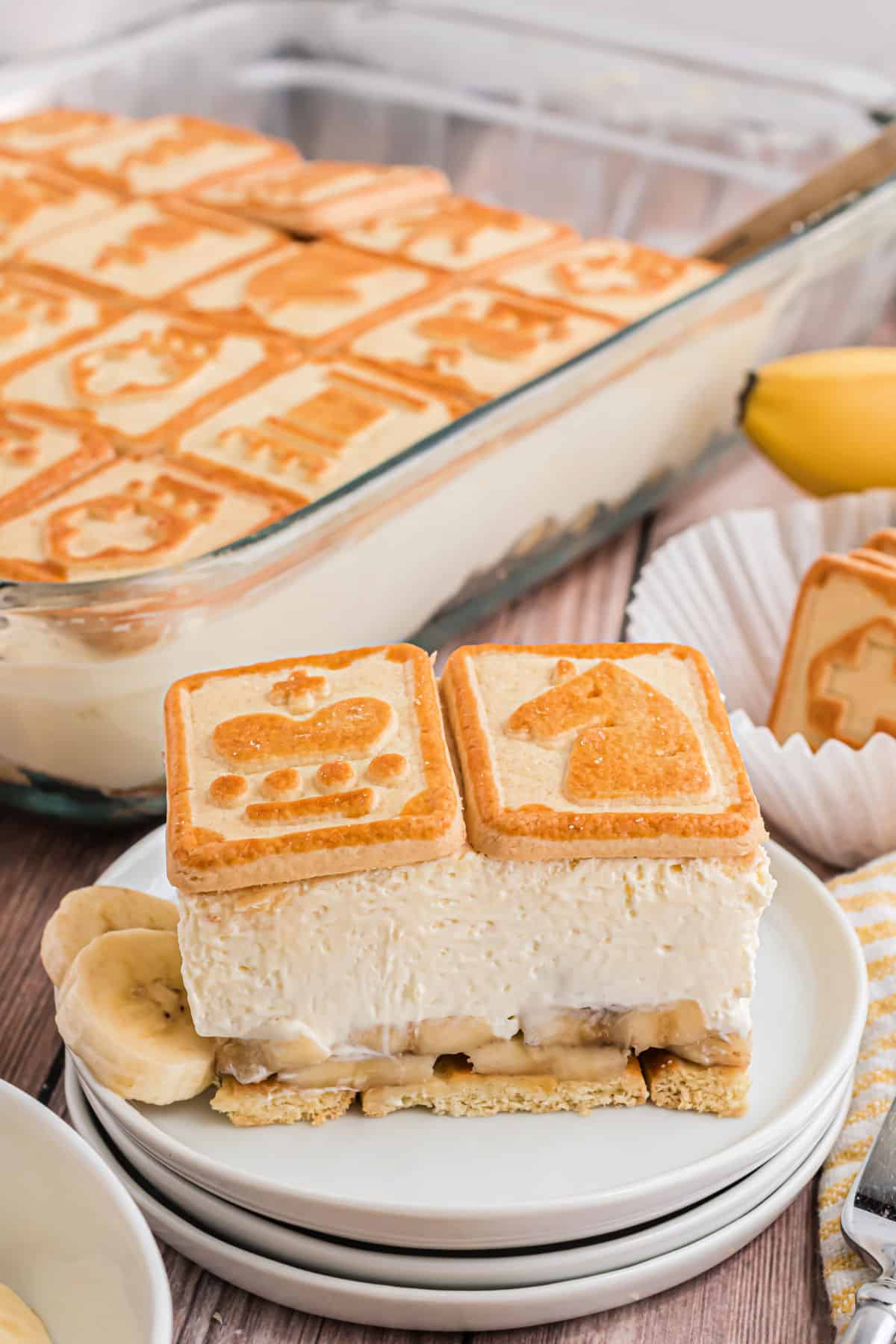 Slice of banana pudding on a stack of white plates.