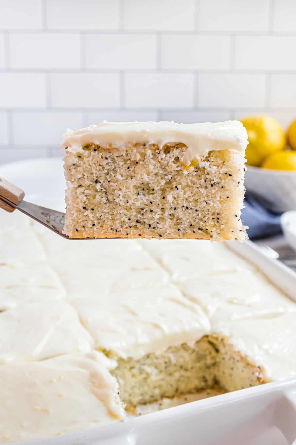 Slice of lemon poppyseed cake on spatula being lifted out of baking pan.