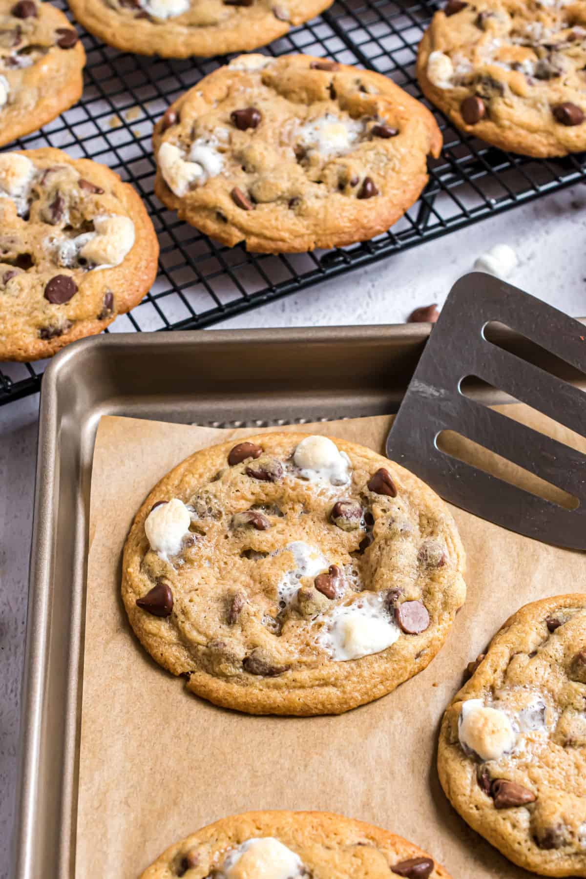 S'mores stuffed cookies on a parchment paper lined cookie sheet.