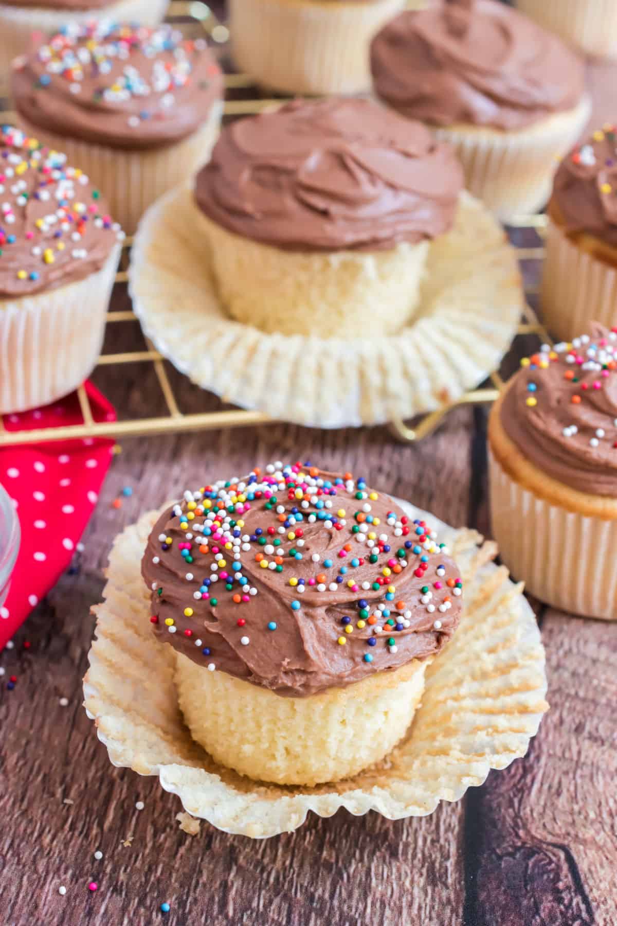 Yellow cupcake unwrapped from liner and topped with chocolate sour cream frosting.