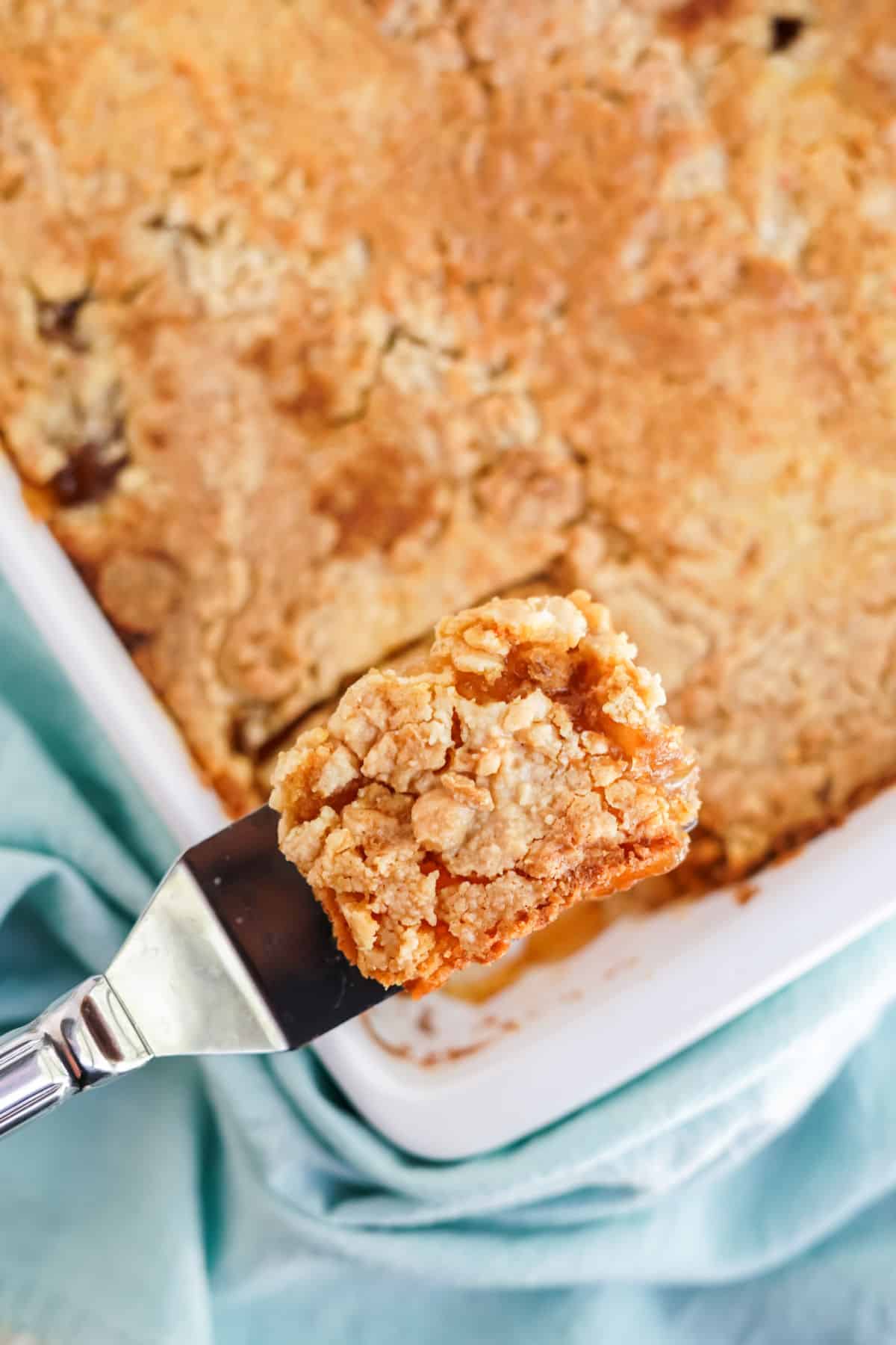 Apple dump cake being lifted out of dish with spatula.
