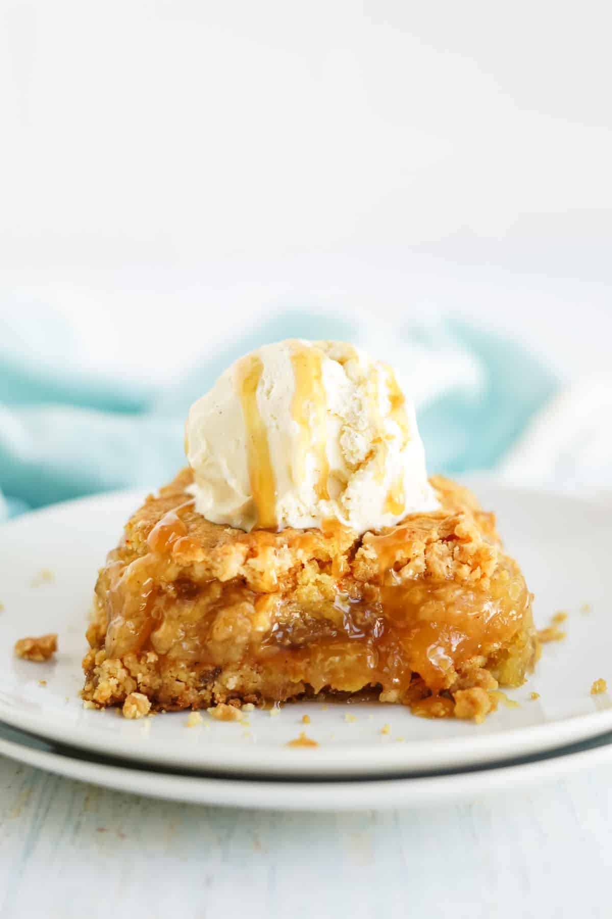 Slice of apple dump cake with vanilla ice cream on a white plate.