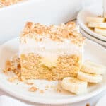 Slice of banana pudding cake with fresh bananas on the side.