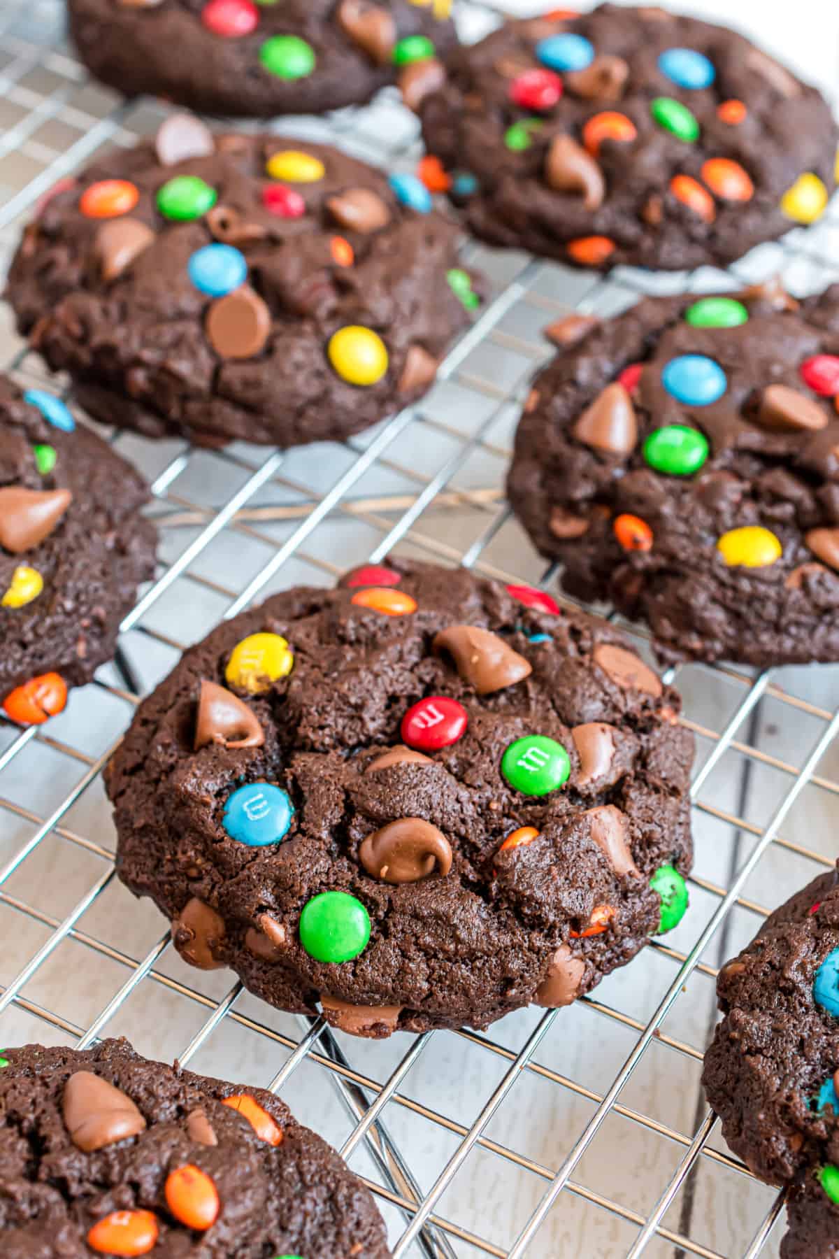 Chocolate cookies with m&m's on a wire cooling rack.