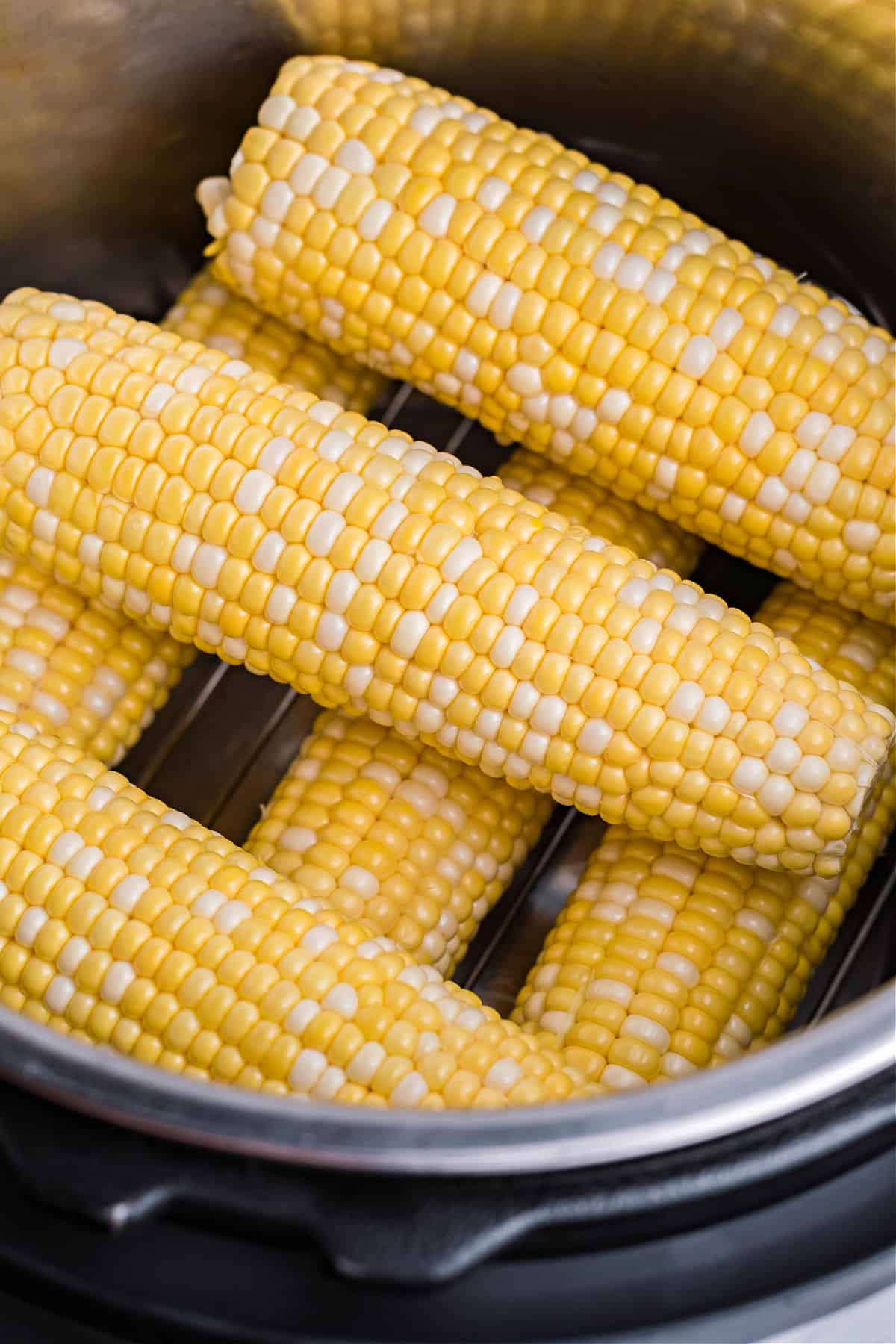 Ears of corn stacked on a trivet inside the instant pot.