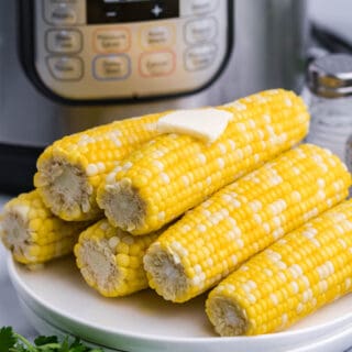 Corn on the cob served on a white plate, stacked on top of each other.