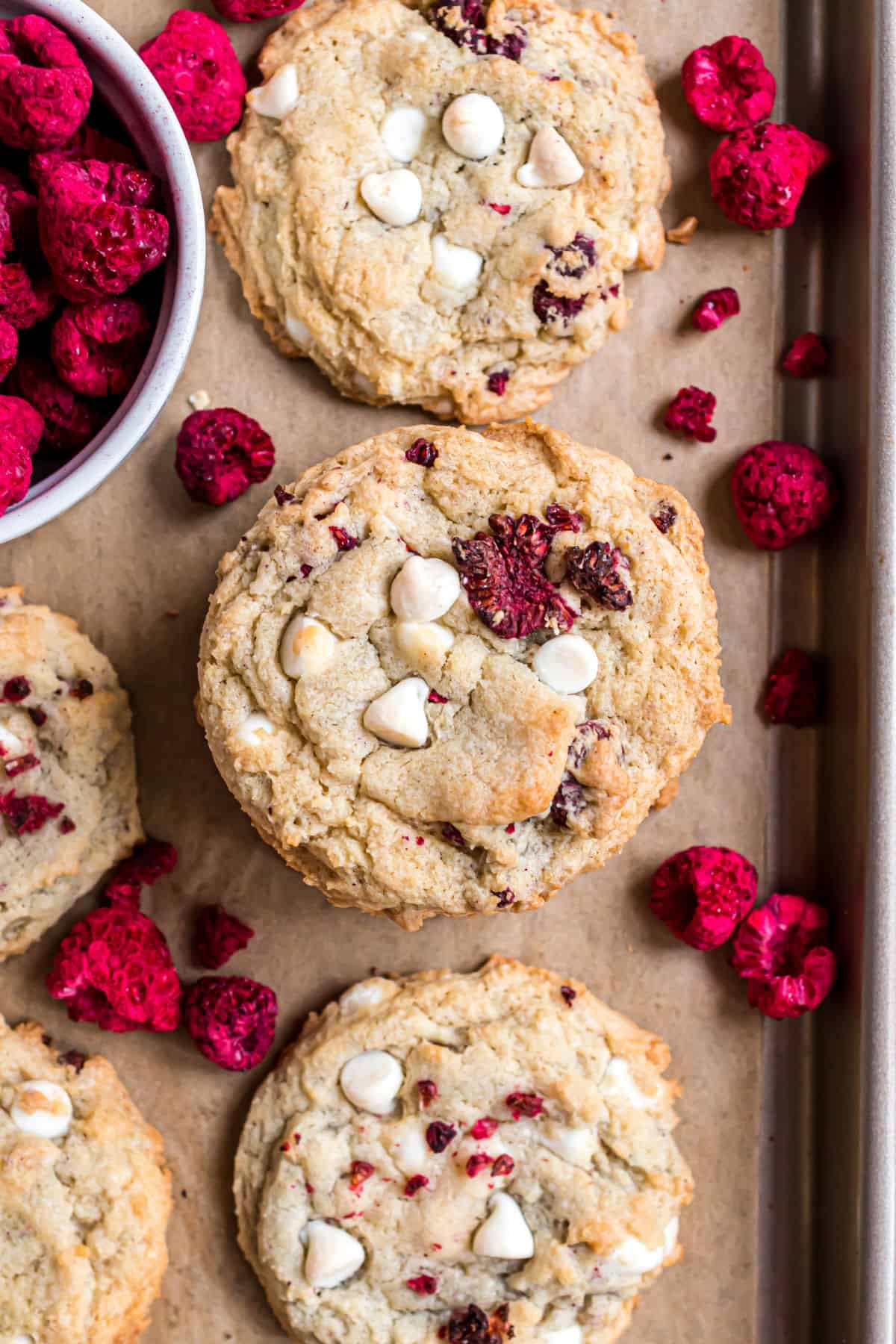 Raspberry cheesecake cookies baked on a parchment paper lined cookie sheet.