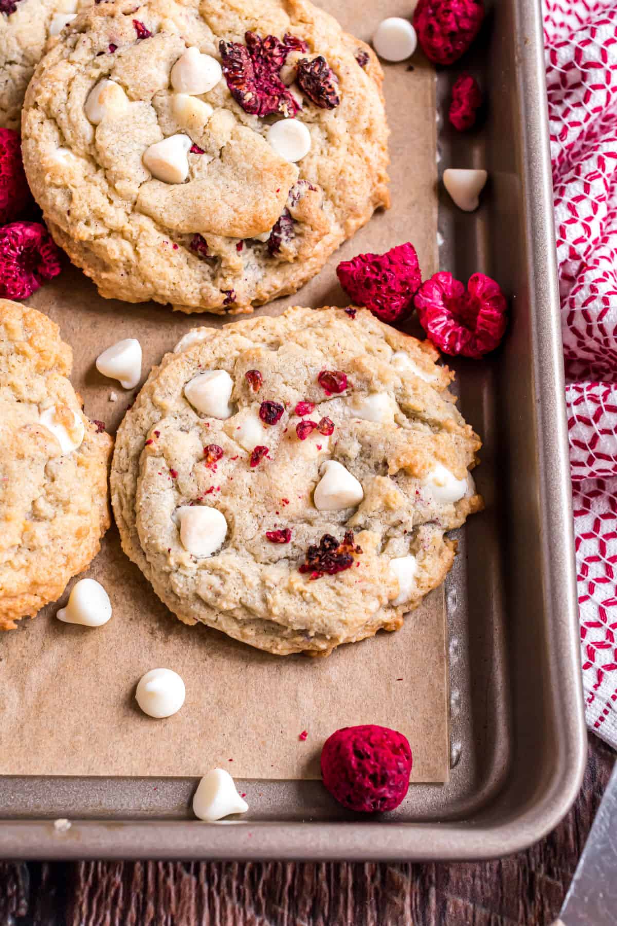 Raspberry cheesecake cookie on parchment paper with white chocolate chips.