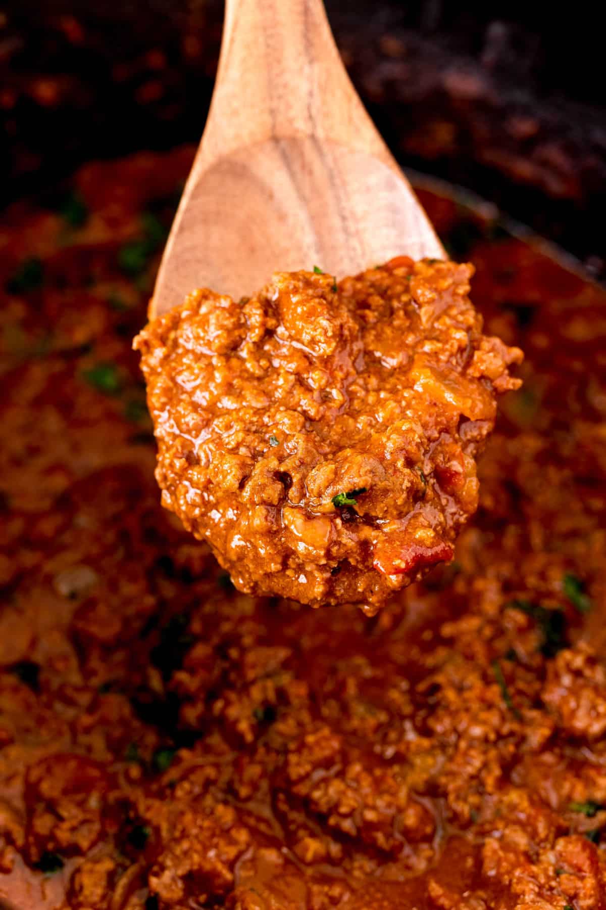 Wooden spoon with cooked taco meat on it.