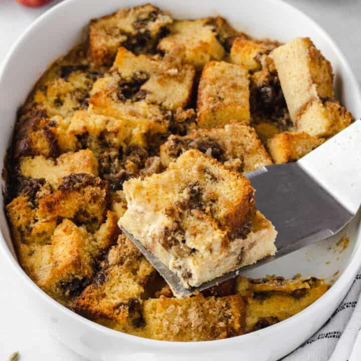 Apple bread pudding in oval baking dish with one slice removed.