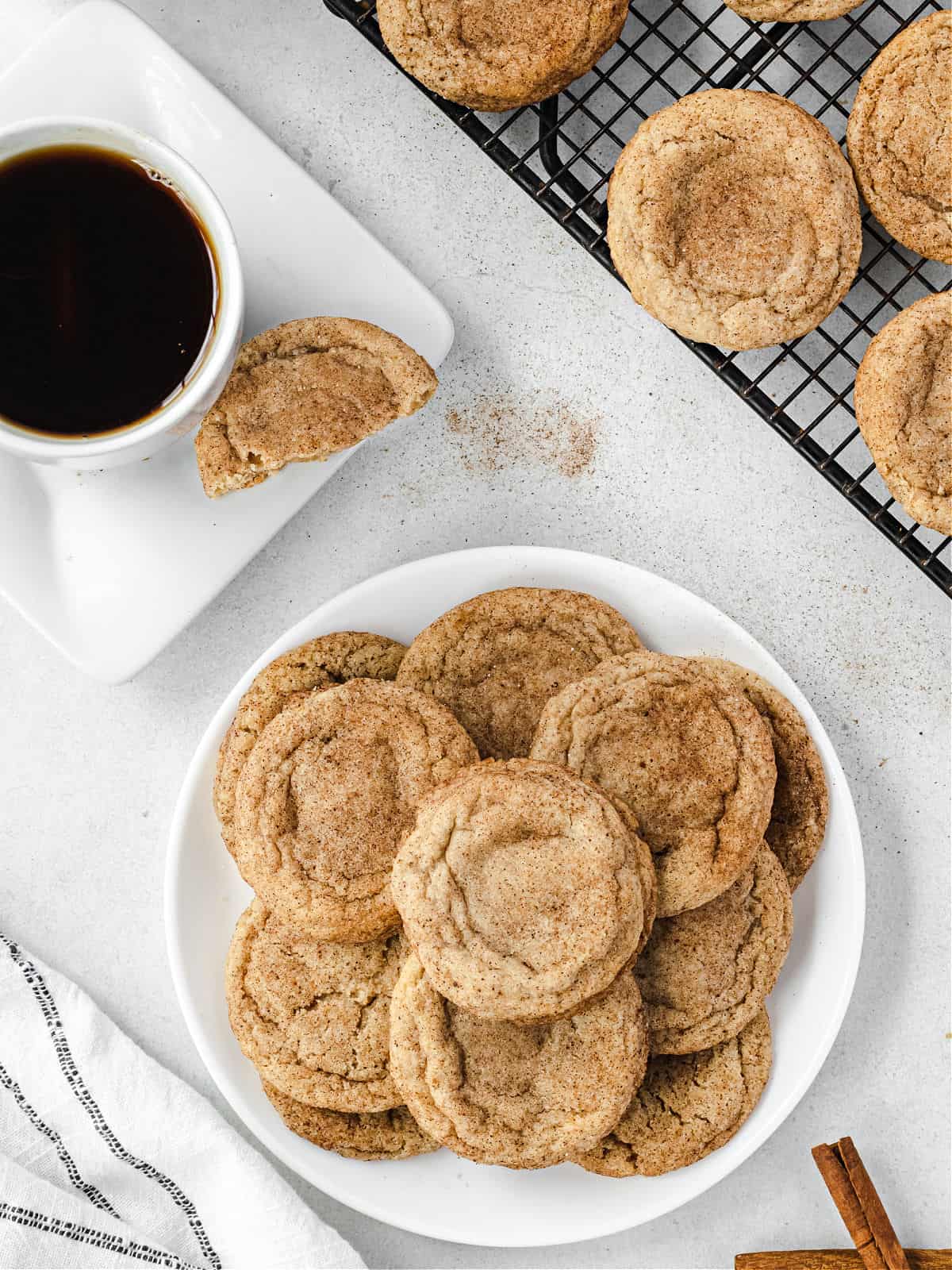 Stack of chai cookies on a plate with a cup of tea in background.