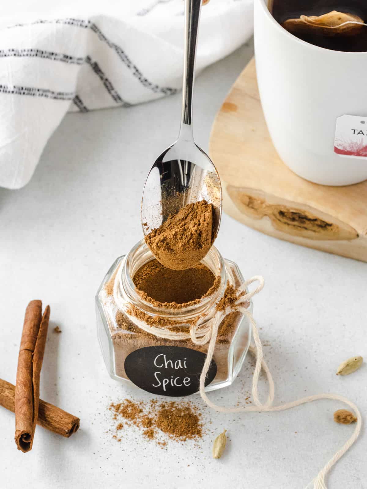 Chai spice in a jar being spooned out.