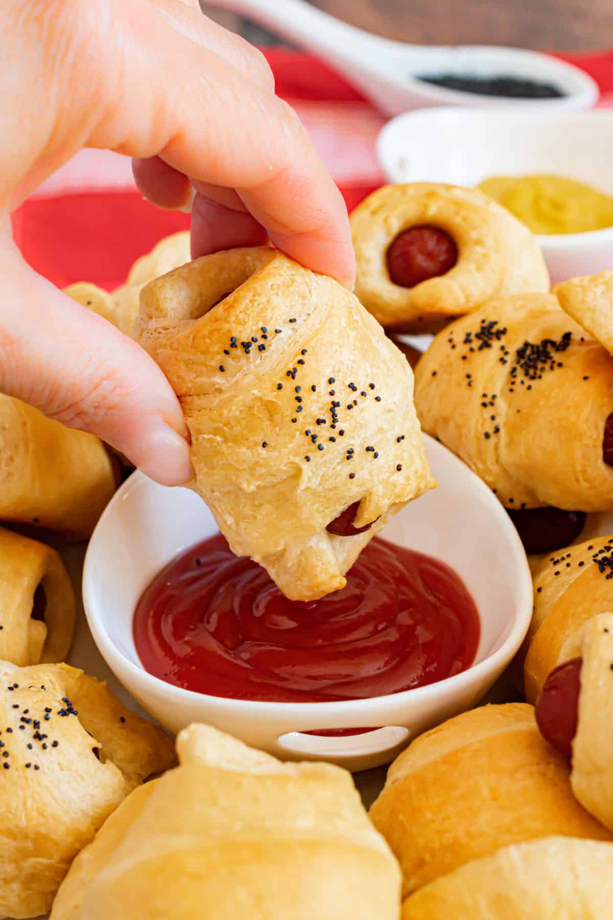 Crescent roll dog being dipped in ketchup.