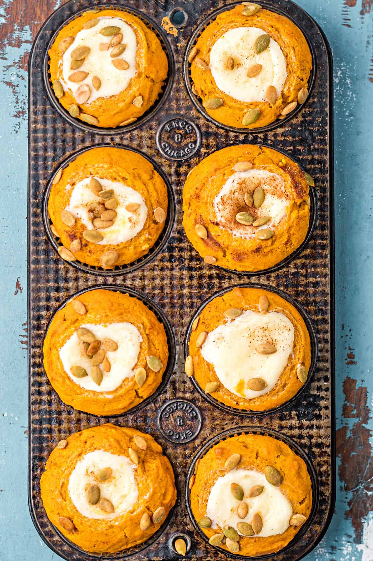 Pumpkin muffins with cream cheese centers and spiced pepitas on top.