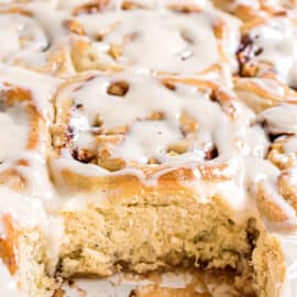 Apple cinnamon rolls in pan with one removed.