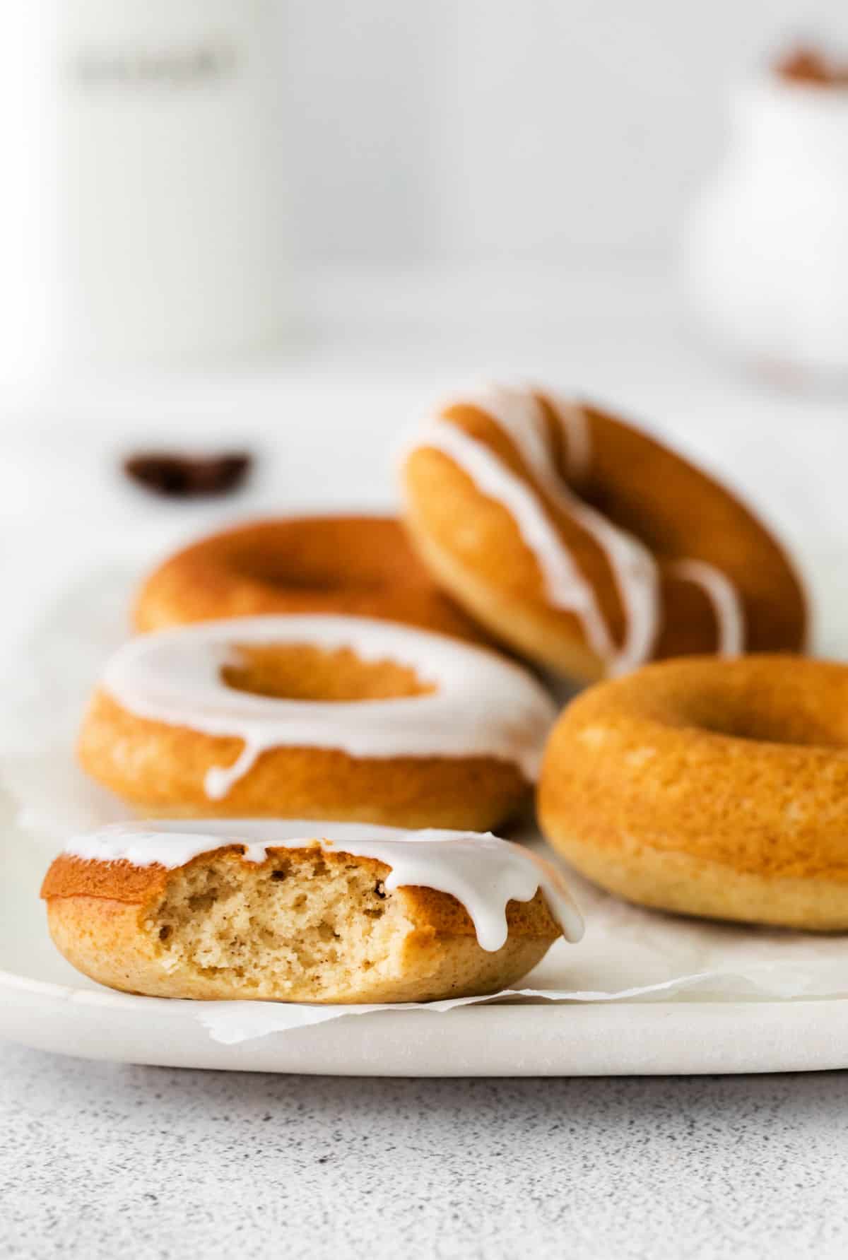 Chai spiced donuts on a plate, drizzled and frosted with vanilla icing.